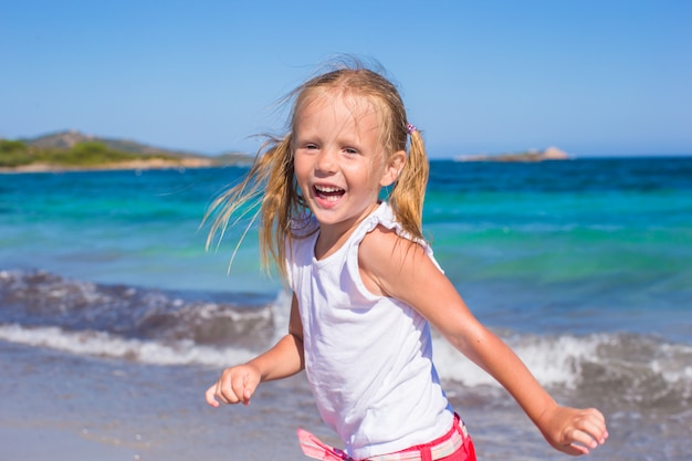 Adorável menina brincando na praia branca durante férias tropicais