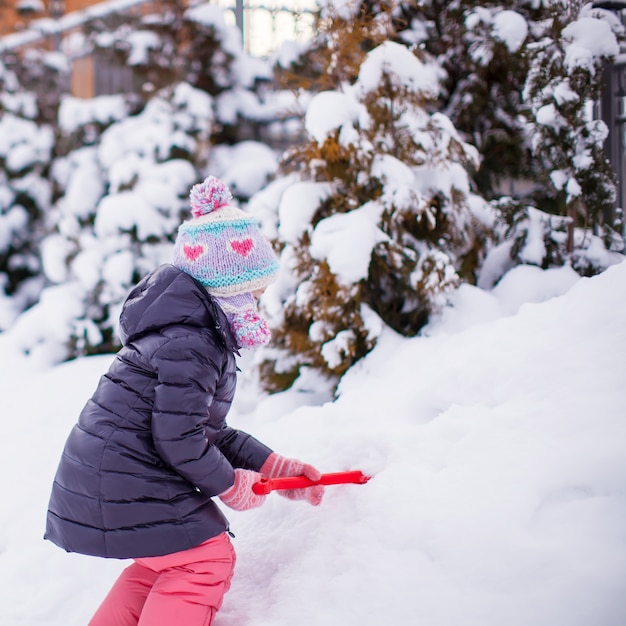 Adorável menina brincar com neve pá em um dia de inverno