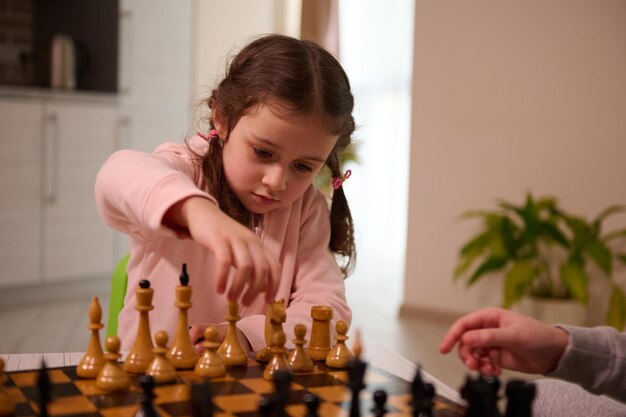 Jovem Mulher Olhando Para As Peças De Xadrez No Tabuleiro E Fazendo  Movimento Enquanto Joga Jogo De Tabuleiro De Xadrez Em Casa Sozinho Foto  Royalty Free, Gravuras, Imagens e Banco de fotografias.