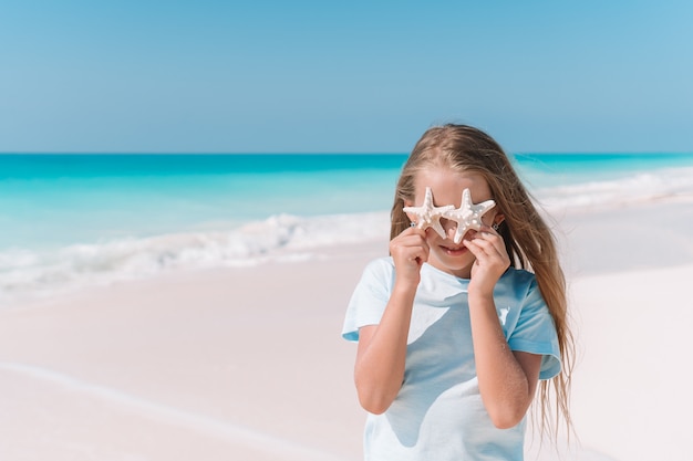 Adorável menina com estrela do mar na praia durante as férias de verão