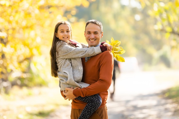 Adorável menina com pai feliz andando no parque outono em um dia ensolarado.