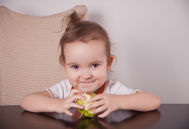 Adorável menina comendo uma maçã verde