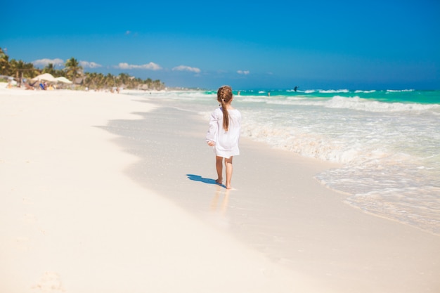 Adorável menina correndo na praia branca exótica no dia ensolarado