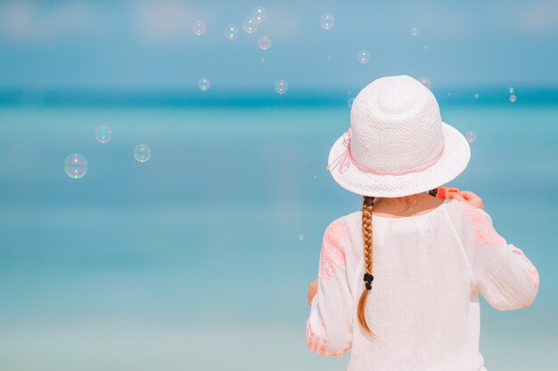 Adorável menina de chapéu na praia durante as férias de verão