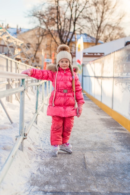 Adorável menina desfrutando de patinar na pista de gelo