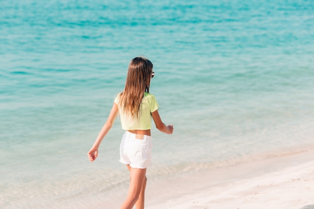 Adorável menina divirta-se na praia tropical durante as férias