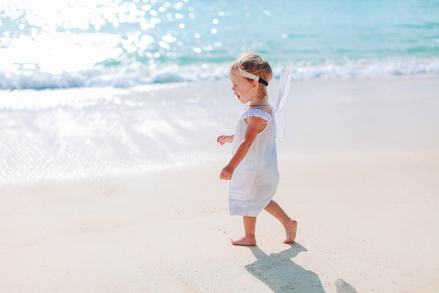 Adorável menina Divirta-se na praia tropical durante as férias