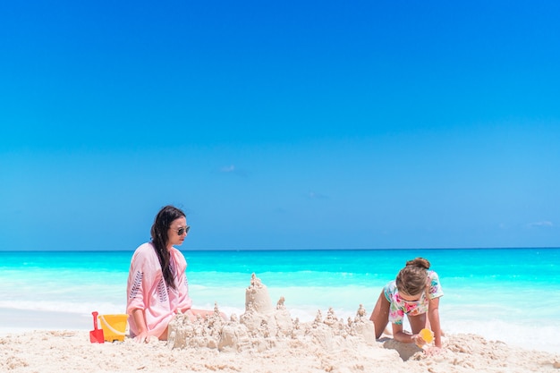 Adorável menina e jovem mãe na praia tropical