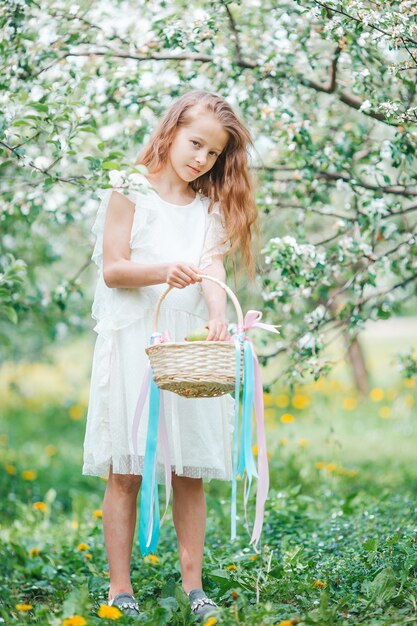 Adorável menina em um jardim de maçãs em flor num lindo dia de primavera