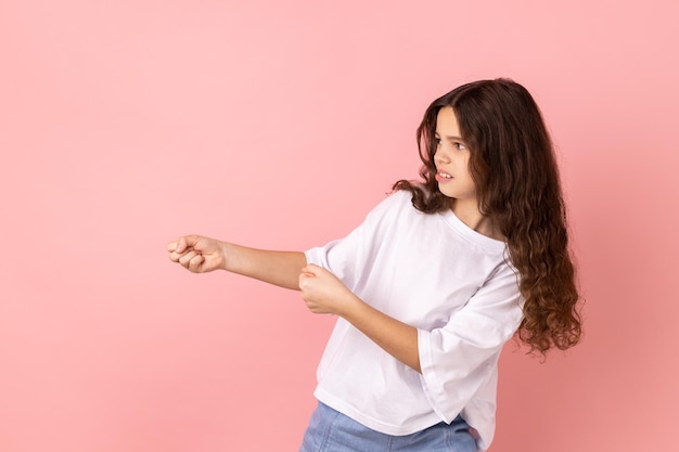 Foto adorável menina encantadora em pé no ataque ou puxando o gesto de mãos e olhando para a frente