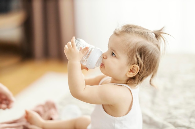 Foto adorável menina está bebendo água da mamadeira