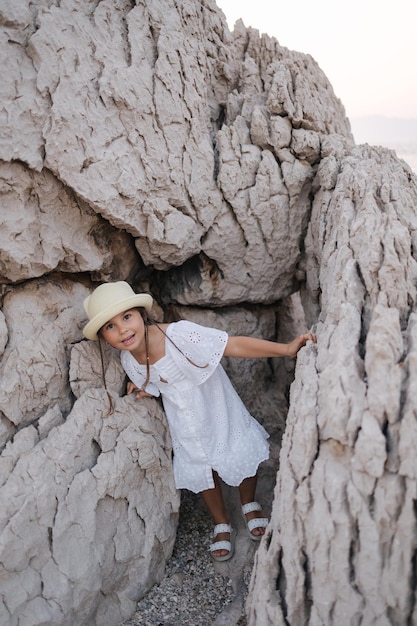 Adorável menina fica entre as pedras e espia para a câmera