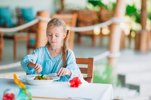 Adorável menina jantando no café ao ar livre