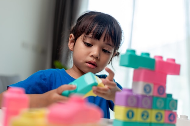 Adorável menina jogando blocos de brinquedo em uma sala iluminada