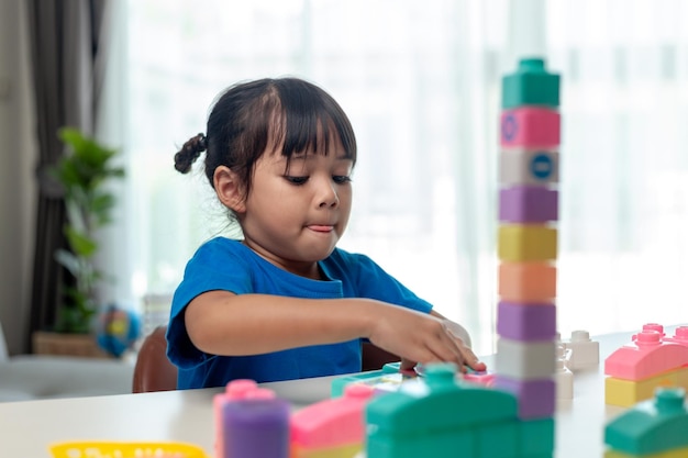 Adorável menina jogando blocos de brinquedo em uma sala iluminada