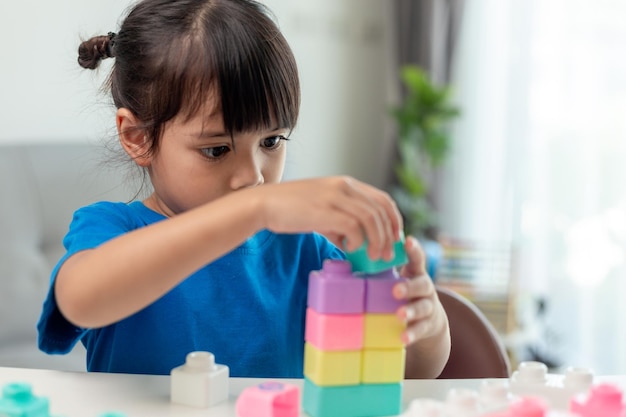 Adorável menina jogando blocos de brinquedo em uma sala iluminada