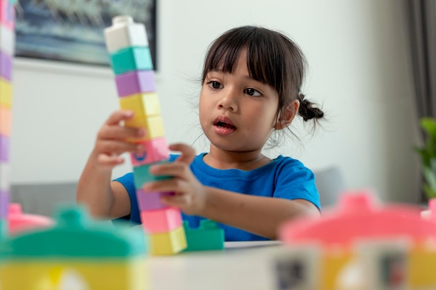 Adorável menina jogando blocos de brinquedo em uma sala iluminada