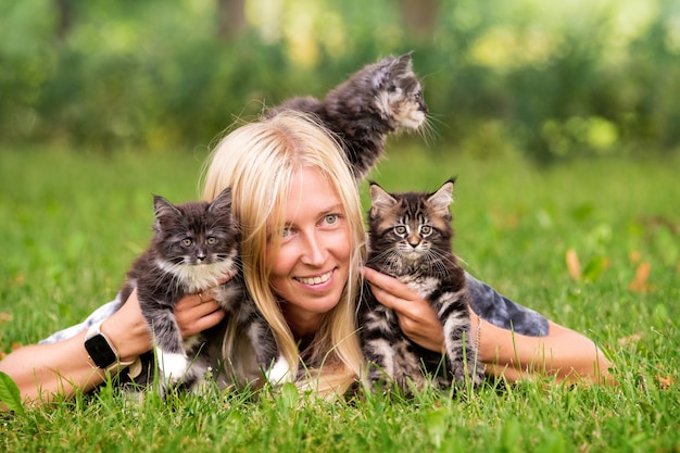 Adorável menina loira brincando com gatinhos em um dia quente e ensolarado de verão