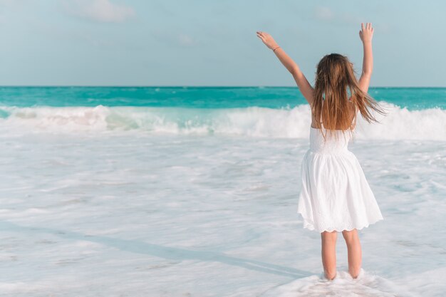 Adorável menina na praia se divertindo muito em águas rasas