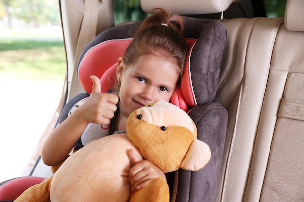 Foto adorável menina no carro com ursinho de pelúcia