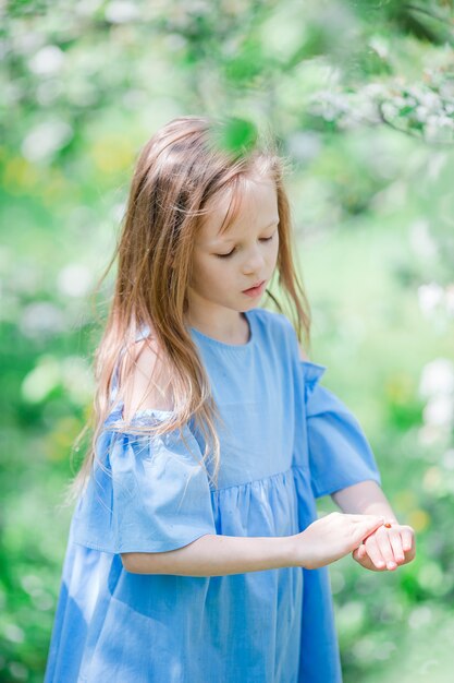 Adorável menina no jardim de apple florescendo em lindo dia de primavera