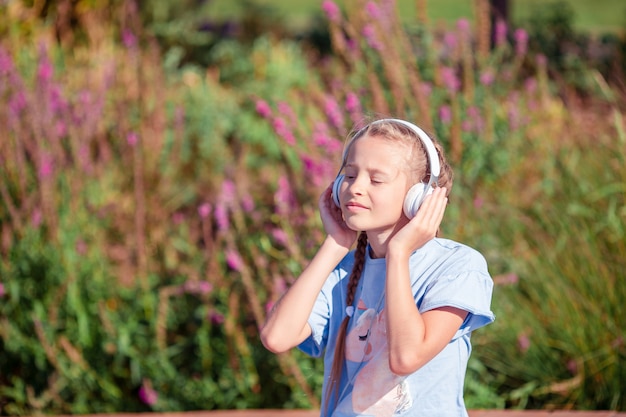 Adorável menina ouvindo música no parque