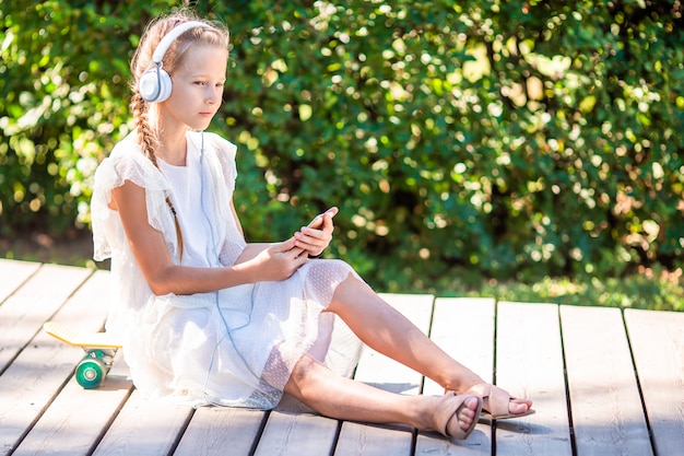 Adorável menina ouvindo música no parque