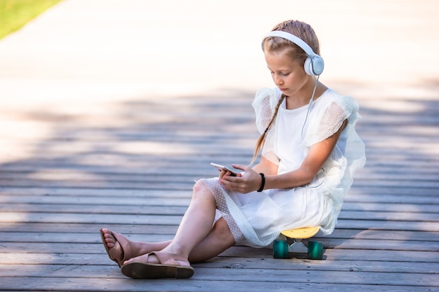 Adorável menina ouvindo música no parque