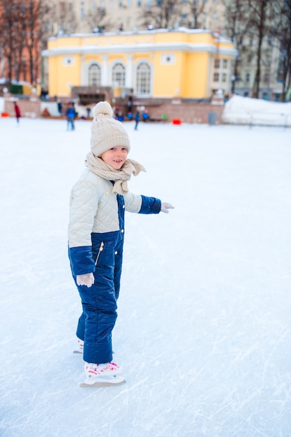 Adorável menina patinando na pista de gelo ao ar livre