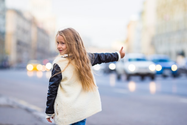 Adorável menina pegar táxi ao ar livre na cidade europeia