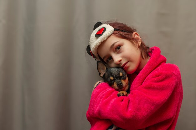 Adorável menina segurando cachorro chihuahua em pé e olhando para cima. garota segurando cachorros chihuahua nos braços. menina de 9 anos com um animal de estimação em casa nos braços. o conceito de amor pelos animais. casa