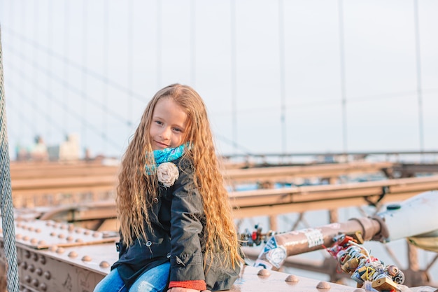 Adorável menina sentada na ponte de Brooklyn em Nova York