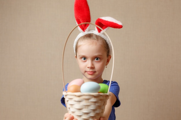 Adorável menina usando orelhas de coelho, brincando com ovos de páscoa