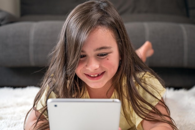 Foto adorável menina usando um tablet digital no chão em casa