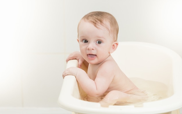 Adorável menino com espuma na cabeça na hora do banho