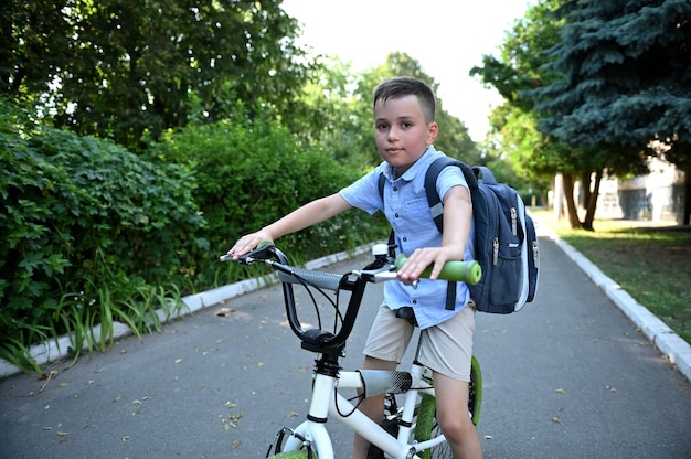 Adorável menino de bicicleta indo para o estabelecimento da escola. crianças andando de bicicleta, crianças andando de bicicleta