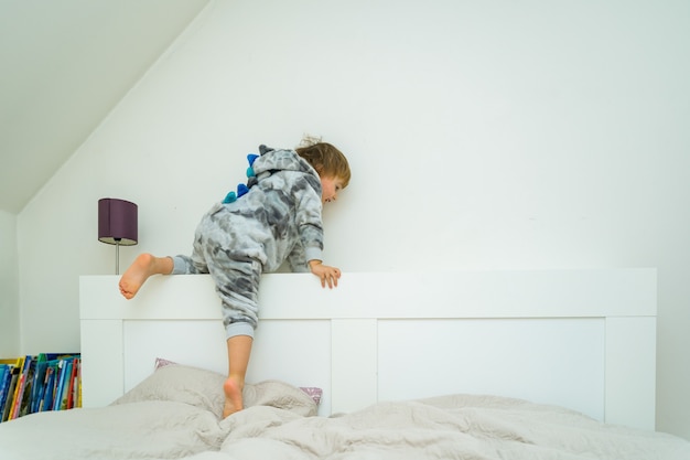 Foto adorável menino de três anos brincando na cama em casa