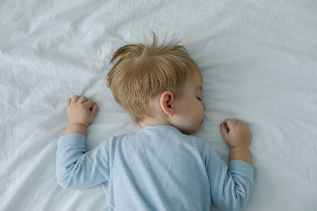 Foto adorável menino dormindo na cama com chupeta na boca