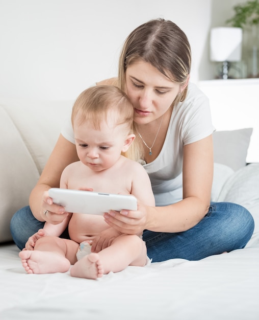 Adorável menino em fraldas usando tablet pc com sua mãe