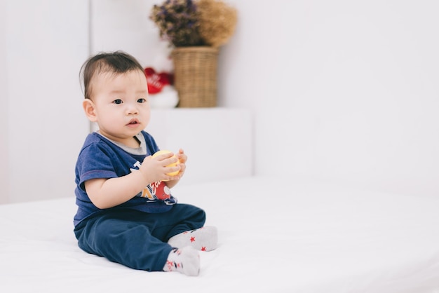 Adorável menino gordinho asiático jogando uma bola de plástico na sala de estar branca Ele se sentindo divertido e olhando para sua mãe e pai Feliz tempo em família no conceito de férias