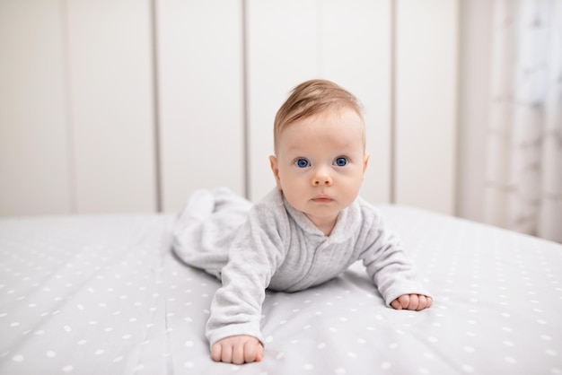 Adorável menino no quarto branco ensolarado Criança recém-nascida relaxando em uma cama