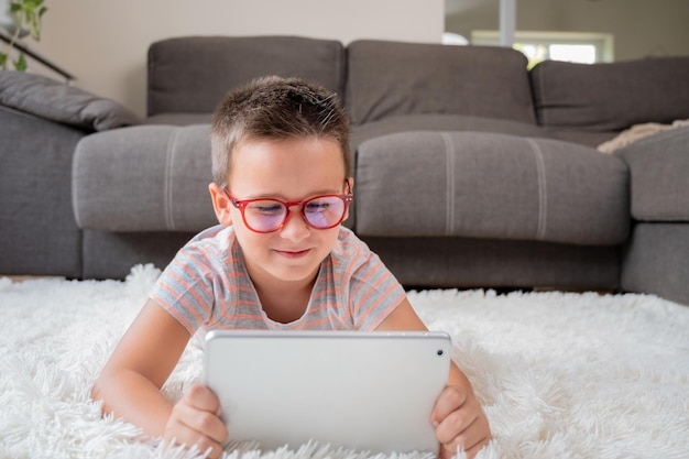 Adorável menino usando um tablet digital no chão em casa