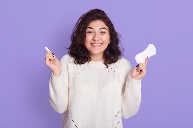 Adorável mulher caucasiana segurando absorvente interno de algodão e absorvente higiênico