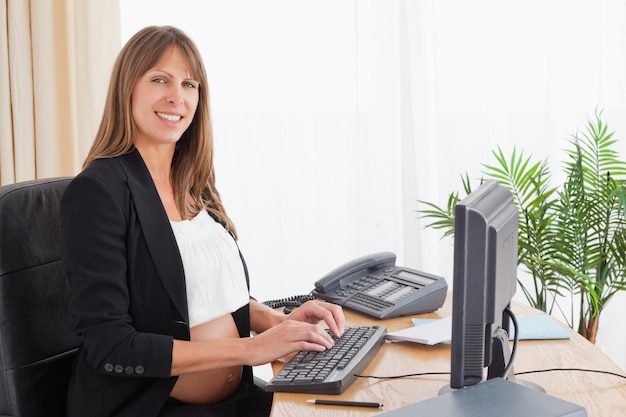 Foto adorável mulher grávida trabalhando com um computador