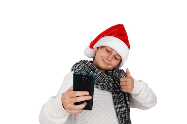 Adorável rapaz sorridente com chapéu vermelho de Natal a tirar uma selfie