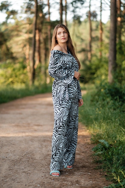 Adorável senhora de vestido de verão na estrada da floresta