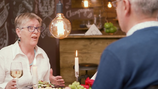 Adorável velhinha contando uma história interessante para o marido durante a hora do almoço. casal de idosos. homem e mulher na casa dos sessenta.