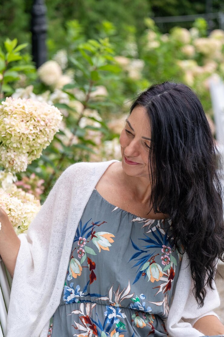 Foto adornada com um vestido floral, uma mulher sorri suavemente entre as hortênsias. seu comportamento reflete o