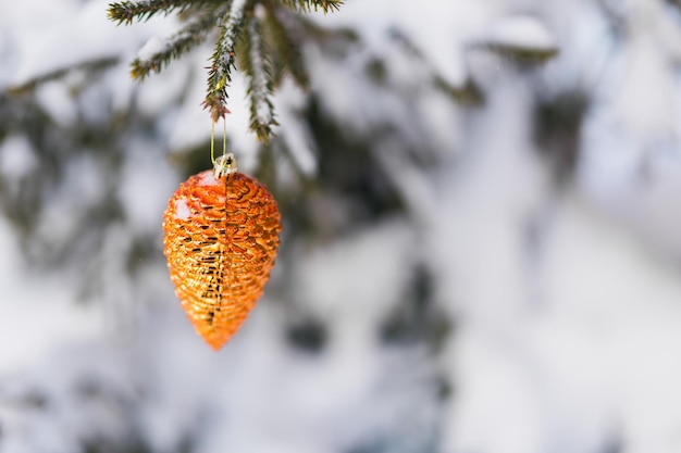 Adorno abeto cono árbol de Navidad decoración juguete colgando de una rama de abeto con ramas de nieve en el fondo Espacio de copia Primer plano