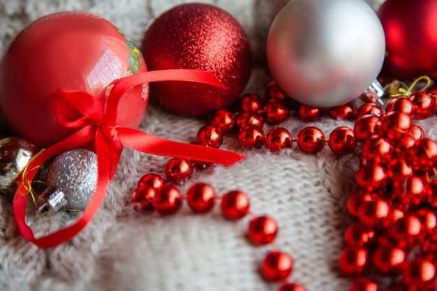 Adorno de natal e decoração de feriado festivo. variedade de enfeites vermelhos brilhantes. bolas e cordão de contas no tecido de malha texturizada.